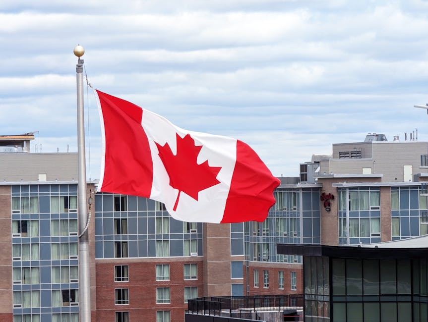 Canadian flag on a pole waving against modern buildings in Halifax, Nova Scotia.