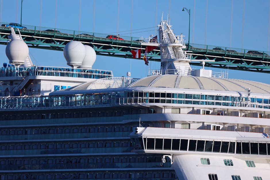 A cruise ship sails under the iconic Vancouver bridge with clear blue skies above.