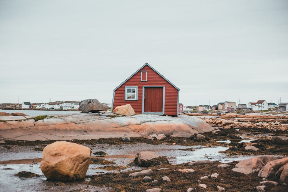 Charming red cabin on rocky shore in rural Fogo Island fishing village, Newfoundland.