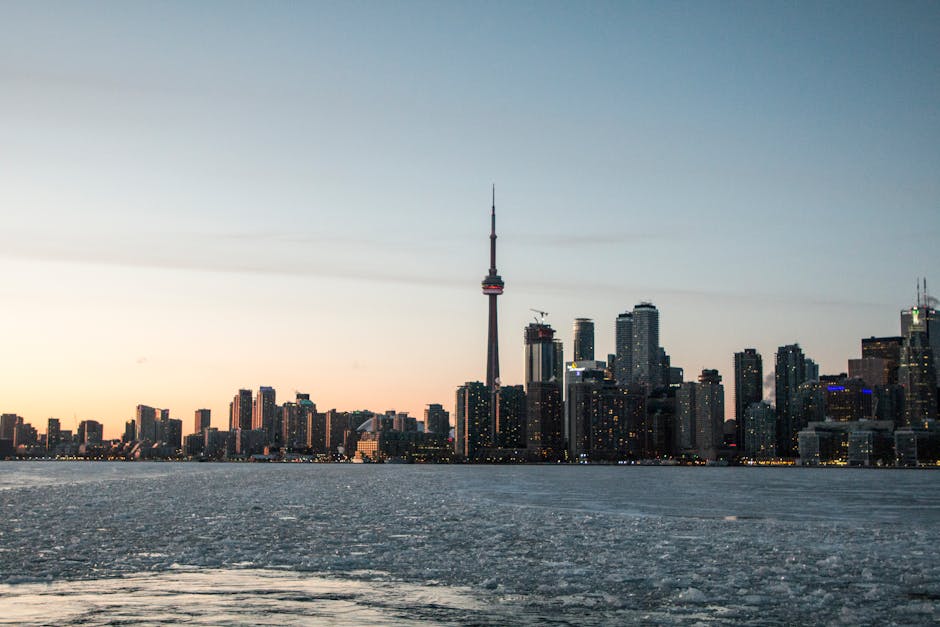 Stunning view of Toronto skyline featuring CN Tower at sunset over Lake Ontario.