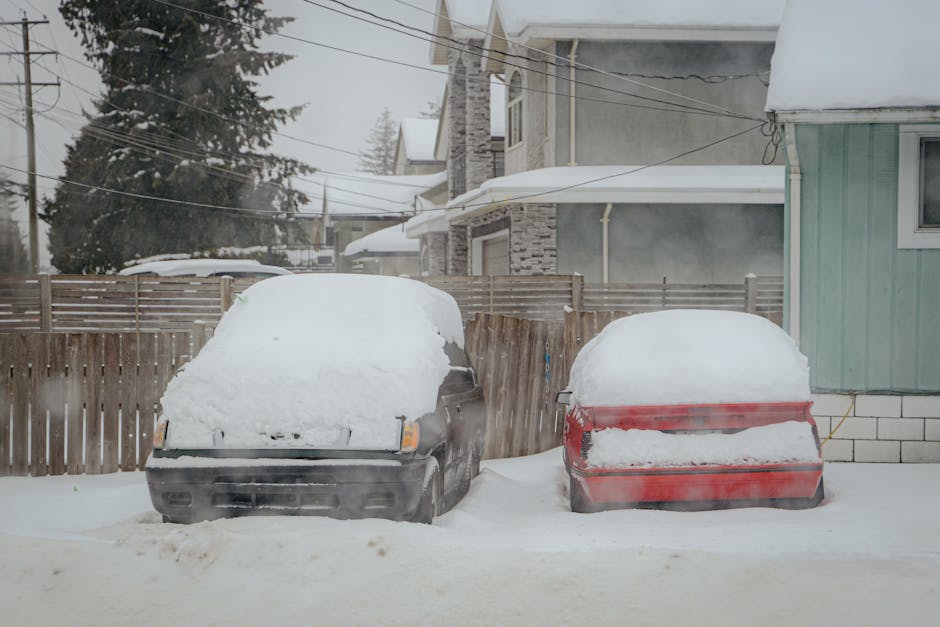 Two snow-covered cars parked on a quiet winter street in Surrey, BC, Canada.