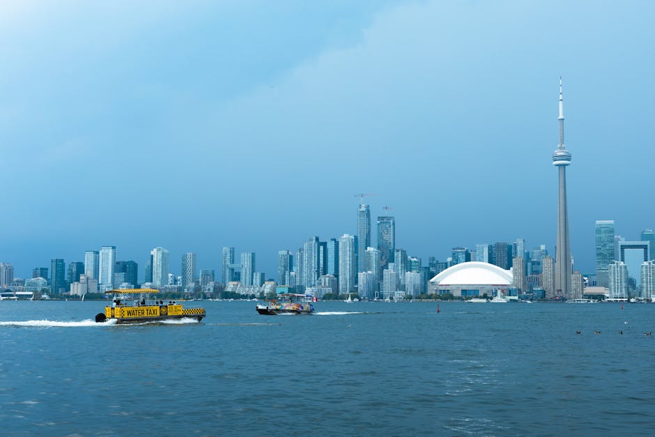 Toronto skyline featuring the CN Tower and water taxi on Lake Ontario under a clear day sky.